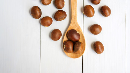 Chestnuts in a spoon on a wooden table.