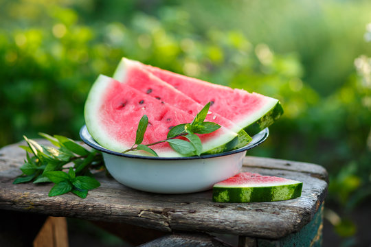 Fresh sliced watermelon in a white bowl outdoors.