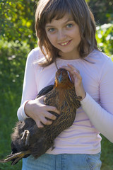 a little girl (little farmer) is holding a hen