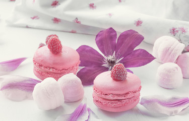 Macaroni with raspberries, marshmallows on a background of beautiful flowers of clematis. Dessert Close-up. Selective focus