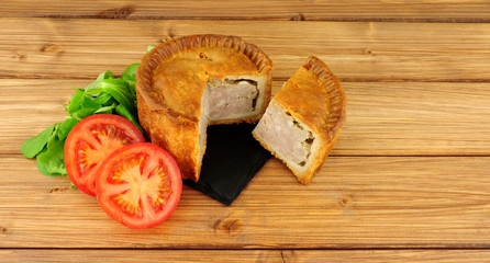 Crusty savoury pork pie on a wood background