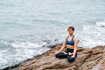 Fototapeta na wymiar Asian woman yoga and meditation on the sea beach.