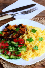 Basmati rice with vegetable stew and fresh salad. Boiled rice basmati, eggplant stew, fresh tomato and cucumber salad with parsley on a plate. Easy vegetarian dish. Vertical photo