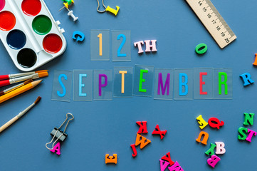 September 12th. Day 12 of month, Back to school concept. Calendar on teacher or student workplace background with school supplies on blue table. Autumn time