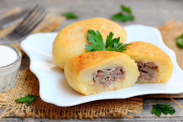 Potato cutlets with mince meat filling on a white plate and a vintage wooden table. Boiled, mashed and seasoned potatoes filled with cooked mince meat filling. Closeup