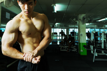 Fototapeta na wymiar Fitness man showing muscular body in gym