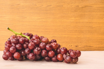 Red grapes on the wooden table. Free space for text