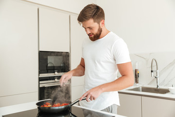 Side view of pleased bearded man cooking