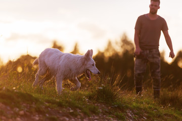 man with a white German Shepherd at the border of a lake