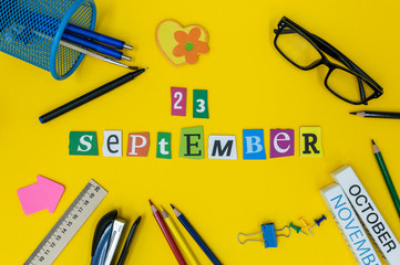 September 23rd. Day 23 of month, Back to school concept. Calendar on teacher or student workplace background with school supplies on yellow table. Autumn time