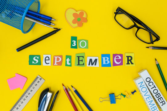 September 30th. Day 30 of month, Back to school concept. Calendar on teacher or student workplace background with school supplies on yellow table. Autumn time