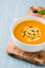 Pumpkin soup in white bowl on blue background
