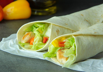 Tortilla wraps with grilled chicken and fresh vegetable. Ingredients on background.