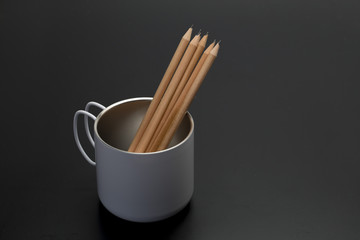 Wood pencil in the cup on back background