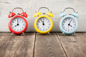 Three colorful alarm clocks on wooden boards