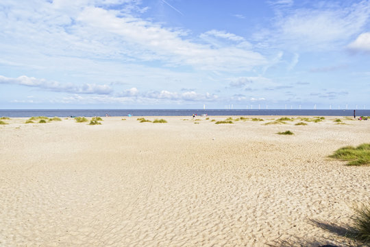 The wide expanse of the deserted Caister-on-Sea beach under a summer sky.