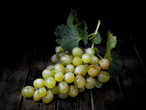 Bunch of white grapes on antique wooden background in light painting