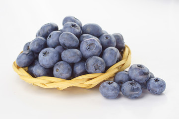 Ripe berry blueberries in a straw plate on a white background