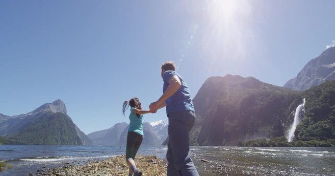 Couple in love having fun outdoors in nature laughing and smiling enjoying active outdoor lifestyle hiking in Milford Sound New Zealand by Mitre Peak in Fiordland.