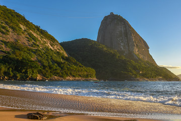 Beautiful sunrise at the deserted Praia Vermelha Beach with the bright sun illuminating the Sugarloaf Mountain at the early morning, Rio de Janeiro, Brazil