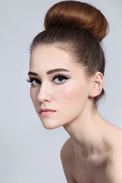 Young beautiful fresh slim girl with clean make-up and hair bun, copy space