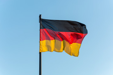 The German flag on a pole with blue sky