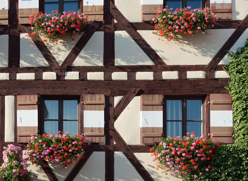 Half-timbered house with several window shutters and flowers