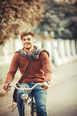 Young handsome man riding bicycle on street.Autumn season.