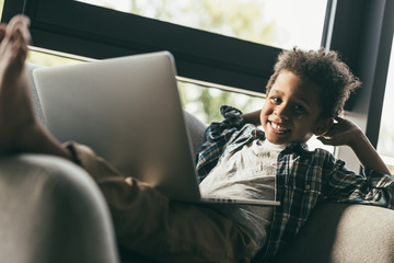 boy with laptop in armchair