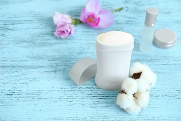 Fototapeta na wymiar Female deodorant and cotton flowers on wooden table