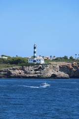 Leuchtturm von Portocolom auf Mallorca, gesehen von den Felsen nahe der Cala Marcal