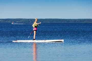 sup - woman on stand up paddle board in the lake