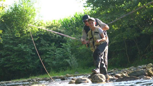 Man teaching son how to fish in river