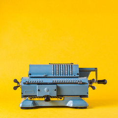 Old calculating machine on yellow background. Accounting or business concept
