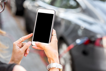 Woman holding a smart phone with empty screen to copy paste with electric car charging on the background