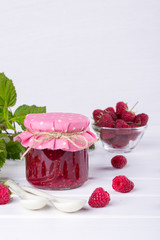 Preserved berry. Glass jar with homemade raspberry jam on a white background.