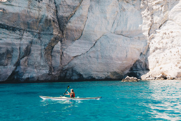 Woman paddles kayak in a calm sea in Sardinia Italy