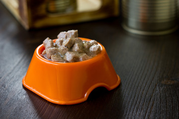 Canned pet food in a orange plastic bowl.