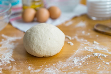 Fototapeta na wymiar Dough, eggs and rolling pin on the kitchen table for cooking. Concept holiday and home comfort.