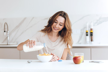 Obraz na płótnie Canvas Pretty healthy woman add milk to her breakfast