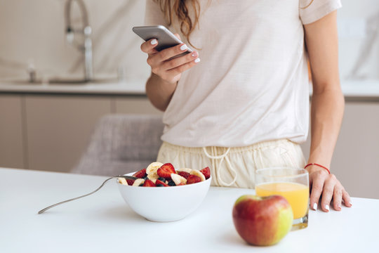 Cropped image of woman with smartphone in the kitchen