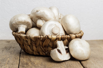 Mushrooms champignons in a wicker basket in a rustic style