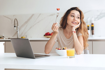 Carefree woman looking aside while eating fruits