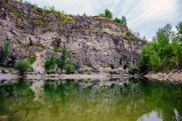 Fototapeta na wymiar Lake with reflection of rocks, natural mountain landscape, abandoned quarry with lake