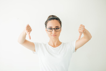 Woman giving thumb down gesture looking with negative expression and disapproval