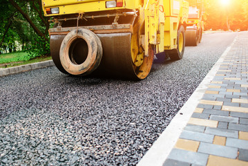 Carrying out repair works: asphalt roller stacking and pressing hot lay of asphalt. Machine...