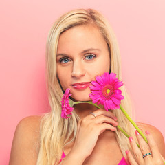 Young woman with flowers on a pink background