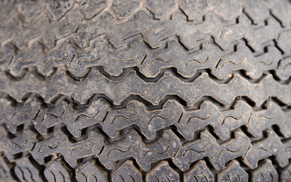 Texture of thick-skinned rubber tire colored in dark gray with carved pattern