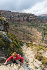 Tourist climbing cliff in the Golden Gate Highlands National Park, South Africa. Adventure and exploration in Africa.