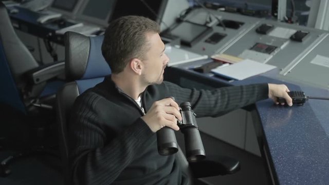 Dispatcher controls the air-traffic with binoculars in control tower in airport